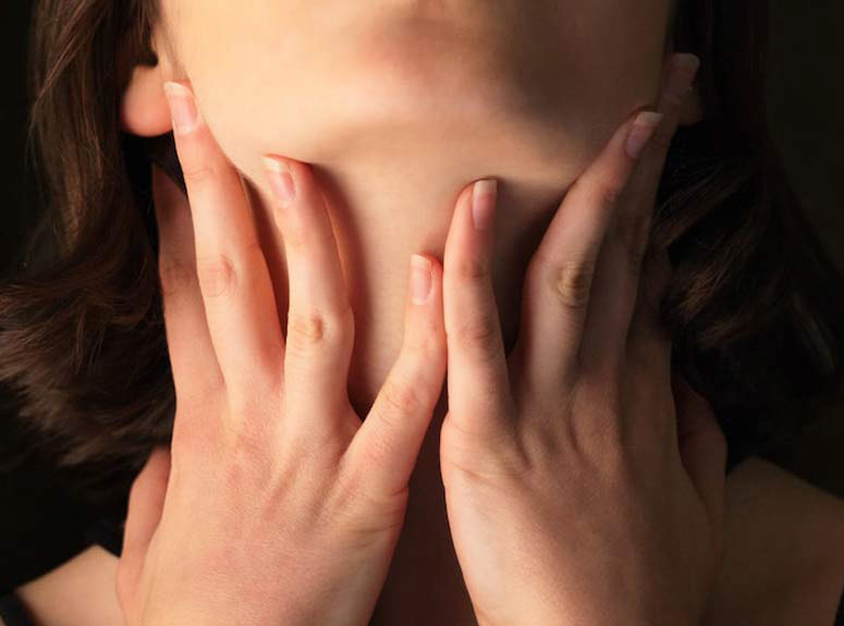 woman feeling throat for signs of hypothyroidism